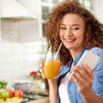 Woman holding smoothie and blood glucose meter, showcasing a natural way to lower blood sugar