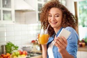 Woman holding smoothie and blood glucose meter, showcasing a natural way to lower blood sugar